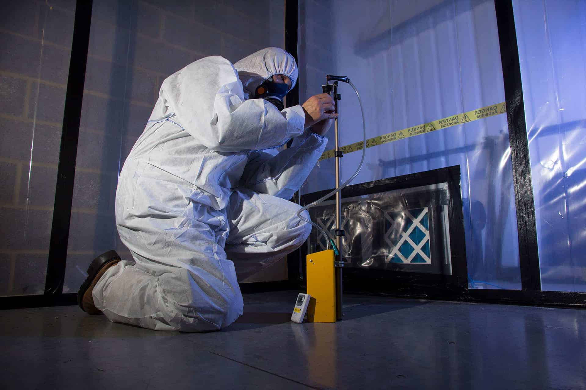 Man in HAZMAT suit taking samples and monitoring air for asbestos