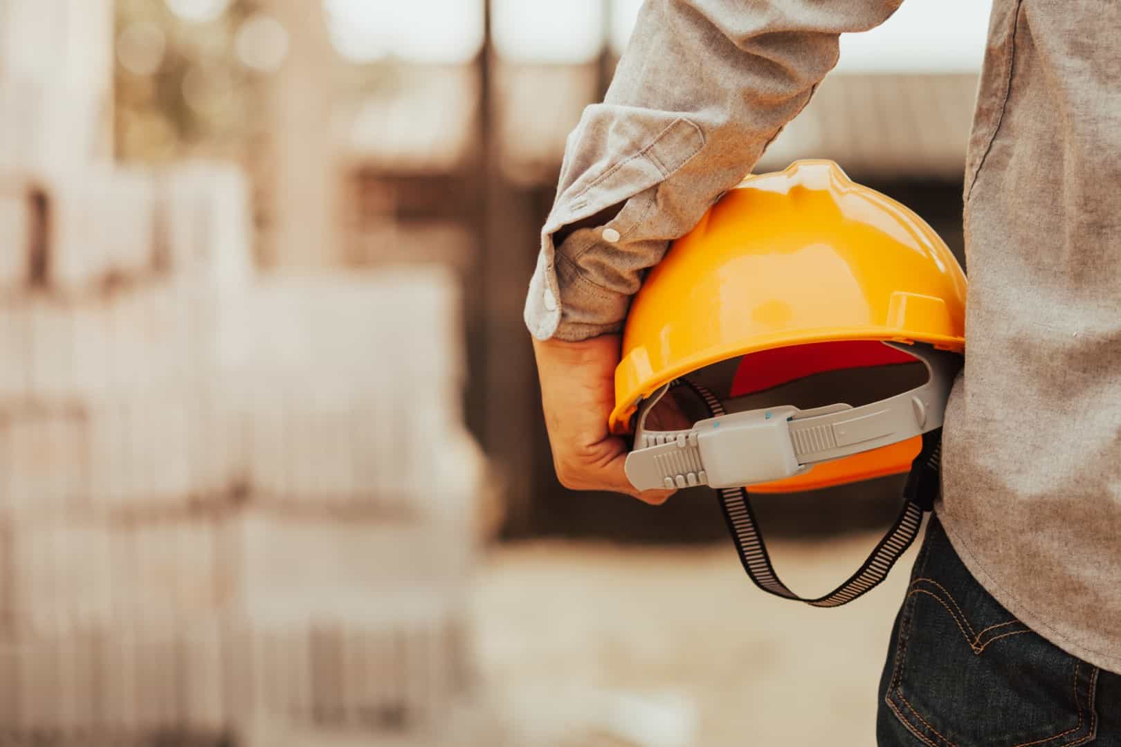 Worker carrying a hardhat to demonstrate workplace health and safety